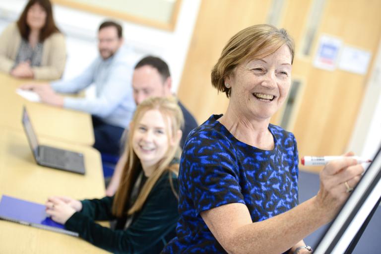 A meeting in a Newark Beacon conference space. One person is writing on a whiteboard.