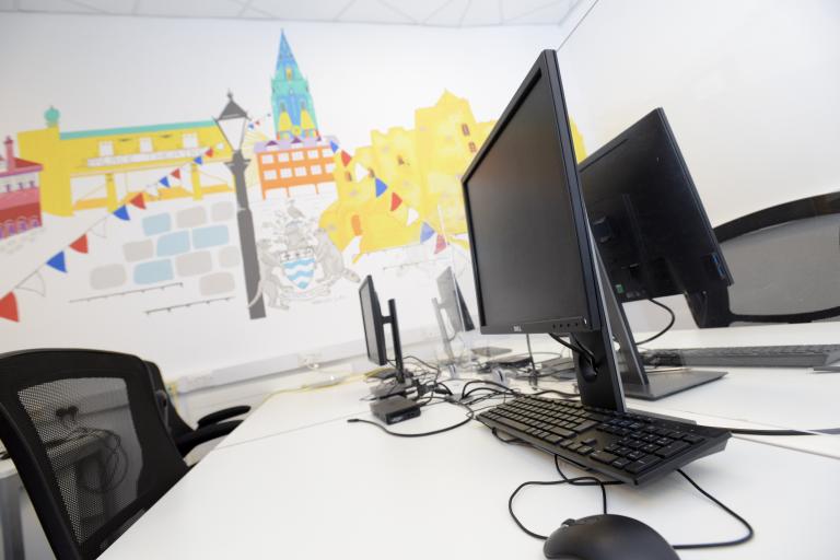 Desks at Newark Beacon, with monitors, mice and keyboards.